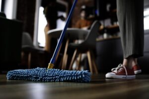 woman cleaning wood floor with dry duster to avoid film-causing floor cleaners